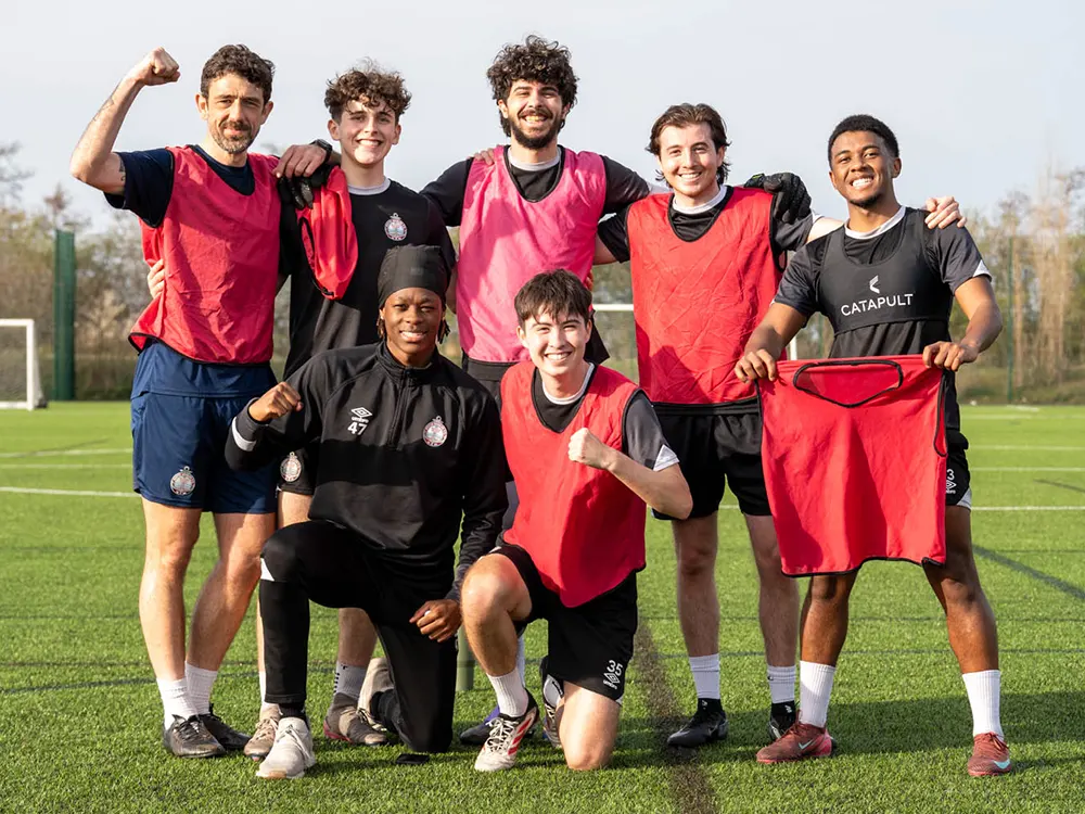 Seven International Academy players pose for a group shot, smiling during training.